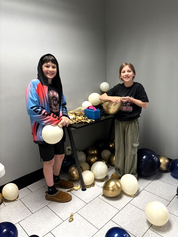 Anchor Homeschool Co-op students blowing up balloons to decorate for an event