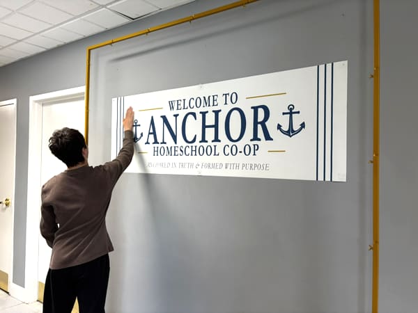 Hanging the Welcome to Anchor Homeschool Co-op banner in Lemont, IL